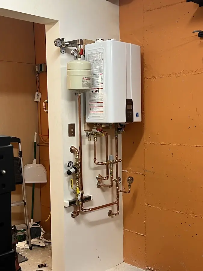 Plumbing technician inspecting water heater connections in Bayville